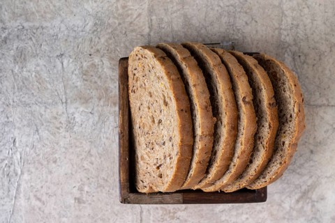 Slices of whole grain bread lie in a square wooden box, copy space, selective focus