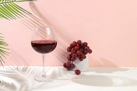 Modern still life with red wine, margarita alcoholic cocktail and grapes on a pastel background