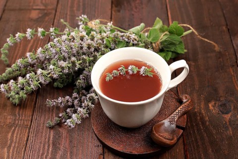 Flower tea with mint on an old wooden table, has a calming and relaxing effect, alternative