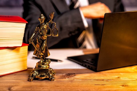 Office of a lawyer with books and a statue of Lady Justice, goddess Justitia, on the desk