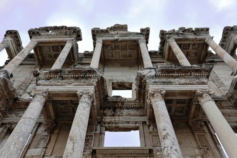 Ruins of an ancient library with impressive marble columns and detailed decorations under a blue