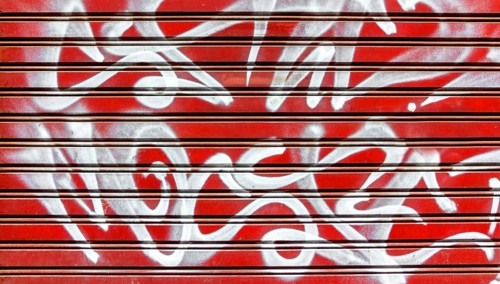 Red garage gate with vandalism sign of graffiti white spray paint. Ideal for concepts and