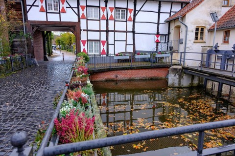 Canal with half-timbered house in the background and autumn leaves on the water, gemen,