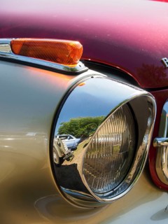 Close-up of a chrome-plated spotlight with reflection of the surroundings on a red background,