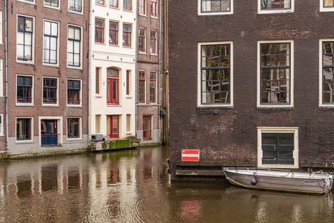 Quiet canal surrounded by traditional buildings with a small boat, Amsterdam, Netherlands