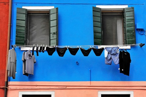 Venice, Veneto, Italy, Europe, Vibrant blue façade with green shutters, contrasting clothing on