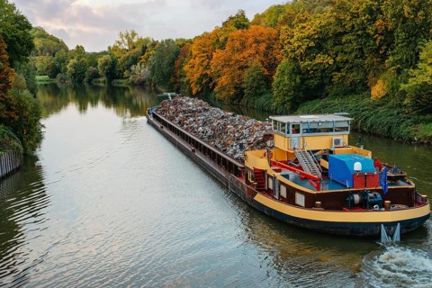 Transportation industry. Ship barge transports scrap metal and sand with gravel. Barge loaded with