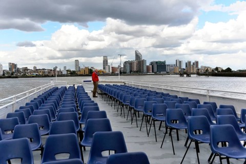River cruise with empty chairs on the deck, modern city view in the background, London, London