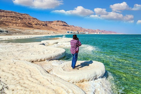 Woman in a plaid cowboy shirt photographs the sea surface. Evaporated salt forms beautiful crystals