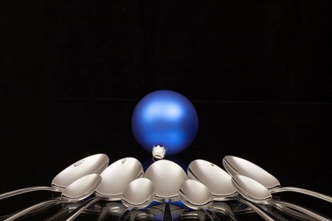 Blue Christmas decoration and nine spoons on a black glass desk