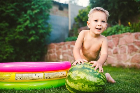 Toddler cute Caucasian white European race boy sitting hugging holding huge watermelon and smiling