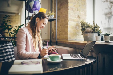 Successful business. Outsource. Woman blogger sits in cafe and uses smartphone, checks email,