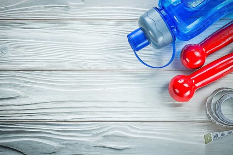 Tape measure water shaker dumbbells on wooden board fitness concept