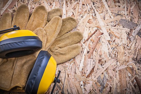 Safety leather gloves earmuffs on chipboard