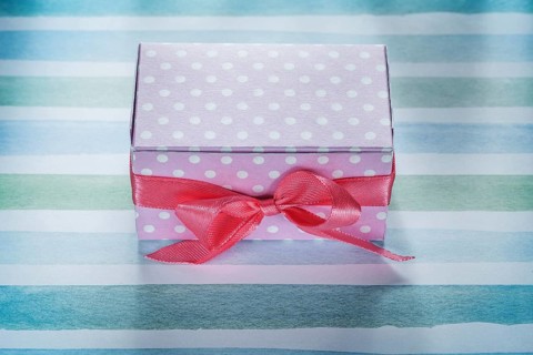 Pink present box on blue striped fabric top view holidays concept