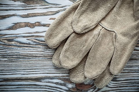 Pair of leather safety gloves on wooden board