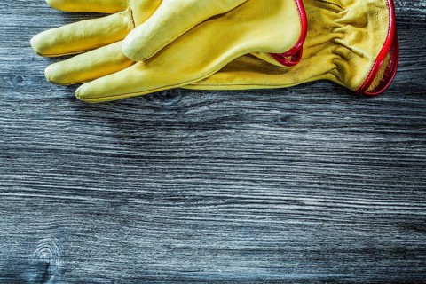 Leather safety gloves on wooden board