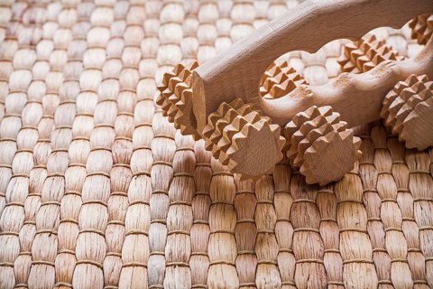 Wooden relaxing massager on wicker background sauna concept