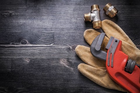 Monkey wrench brass plumbing fittings leather safety gloves construction concept