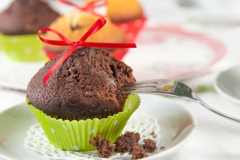 Lovingly decorated muffins on a coffee table. In the foreground, a chocolate muffin with a red bow
