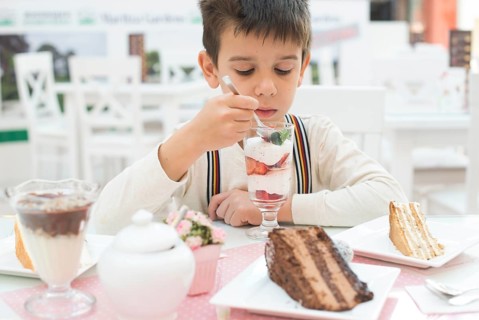 Child eat strawberry smoothie. Choco Cake on a table