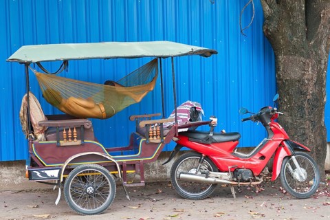 A Cambodian driver sleeps in hammock in his tuktuk