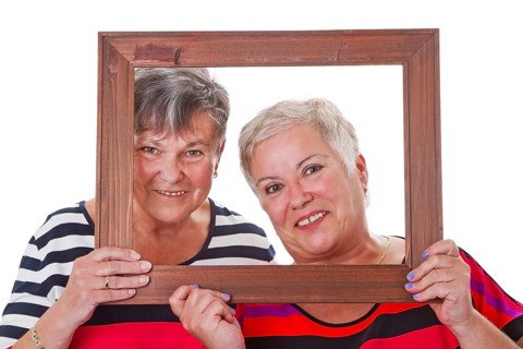 Two senior women looking through a picture frame Two senior women looking through a picture frame