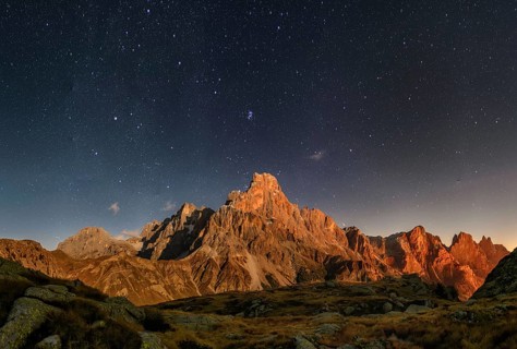 Cimon delle Pala mountain above Passo Rolle with clouds at night with stars