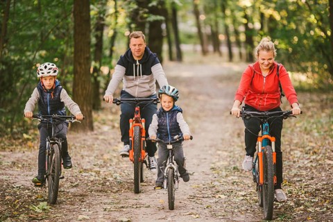 Parents and kids cycling on forest trail. family in warm clothes cycling autumn park. Family