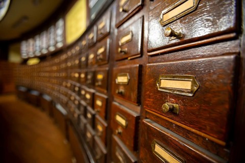 Wooden drawers with metal ornaments in an old-fashioned library. Wooden boxes with index cards in
