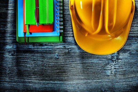 Set of notebooks pen hard hat on wooden board