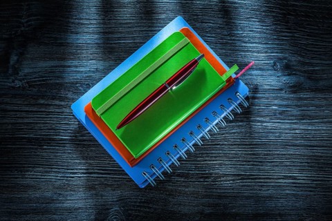 Pile of notebooks pen on vintage wooden board