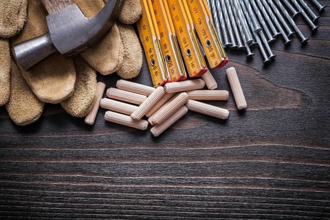 Wooden meter heap of dowels claw hammer leather protective gloves and metal nails on vintage wood