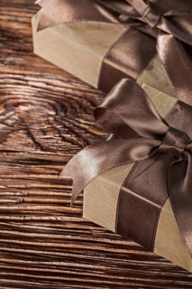 Brown present boxes with tied bow on vintage wooden board