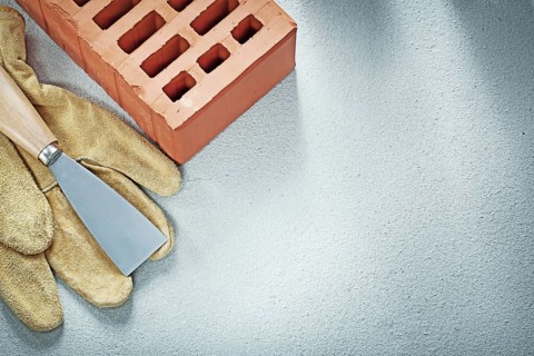 Building bricks leather safety gloves paint scraper on concrete background bricklaying concept