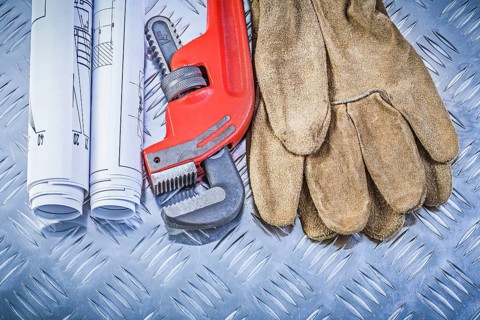 Monkey wrench construction drawings leather safety gloves on corrugated metal background building
