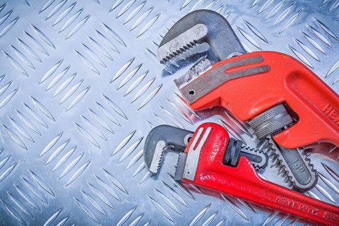 Set of pipe wrenches on fluted metal plate construction concept