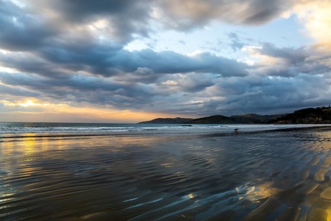 Sunrise over the ocean. Low tide. Strips of sand and water left by the ocean tide. New Zealand,