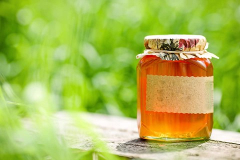 Honey jar on table against nature background