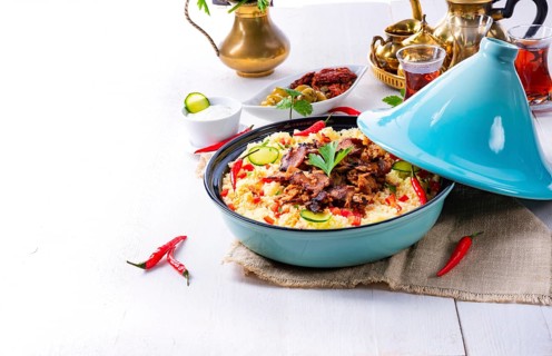Tajin with couscous, vegetables and meat on a white background