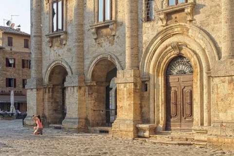 A tourist takes a photo into the sun on the Town Square Piazza Grande of Montepulciano, Tuscany,