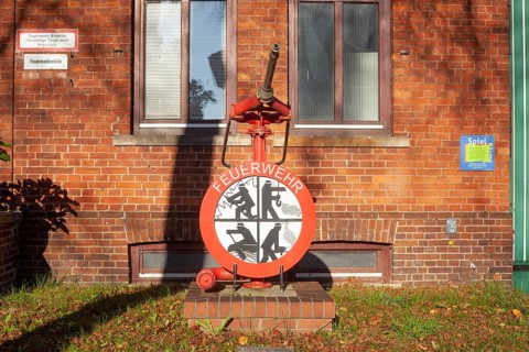 Fire brigade sign with fire pump in front of the building of the voluntary fire brigade in