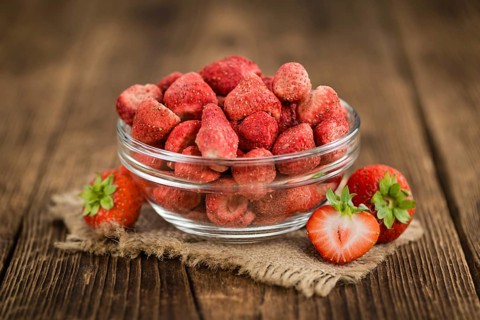 Strawberries (dried) as high detailed close-up shot on a vintage wooden table, selective focus