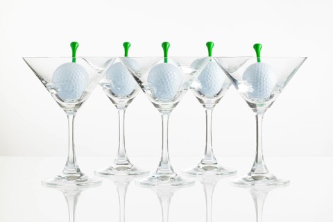 Five glasses of champagne and golf equipments on the glass desk