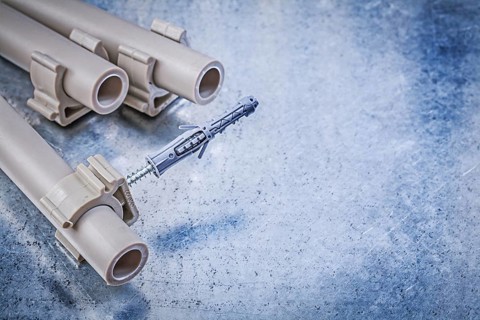 Plastic water pipe clamps on metallic background construction concept