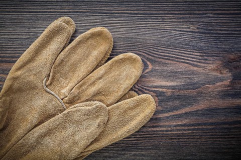 Pair of leather protective gloves on vintage wooden board agriculture concept
