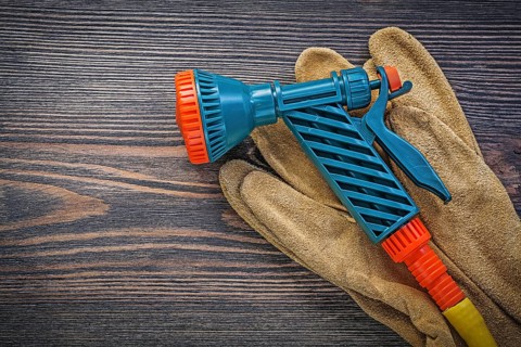Water sprinkler safety gloves on wooden board agriculture concept