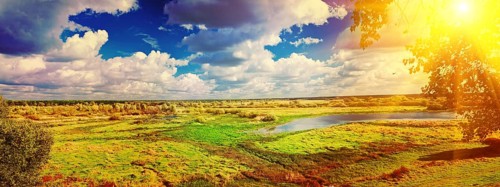 Panoramic view on big meadow with small flood sky with sun instagram stile