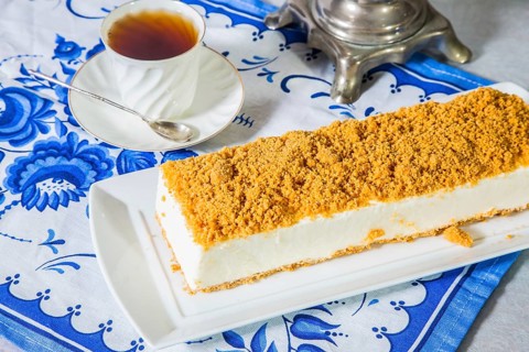 Professional bakery. Exquisite white cheesecake, sprinkled with sweet orange crumbs. The background