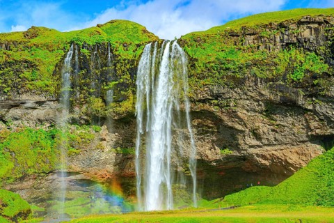 The famous Seljalandsfoss waterfall. Travel to exotic Iceland. Magnificent rainbow appears in the
